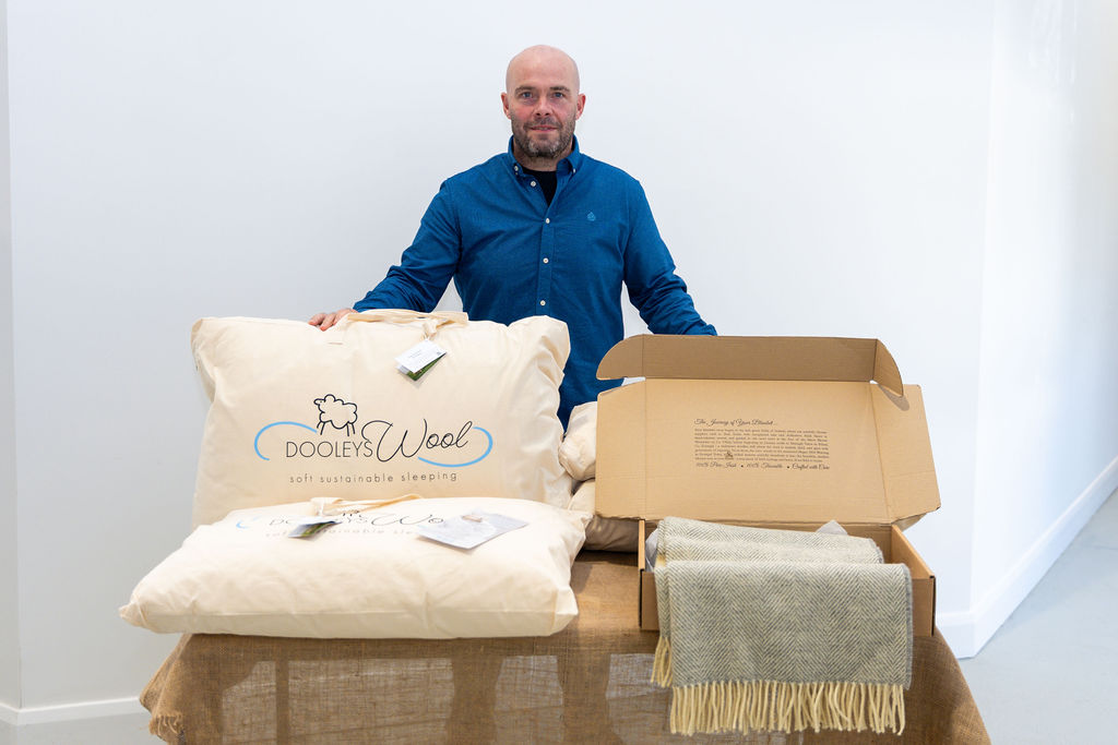 Kevin Dooley, owner of Dooleys Wool with a blanket and two wool pilloews